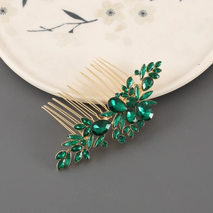 Detailed close-up of a vintage golden hair comb with dark green rhinestone leaves