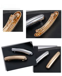 Detail showing glossy gold and silver curved hair clips with metal spring clip back