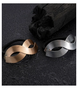 Macro detail of gold and silver mobius loop hair ties with brushed metal texture and elastic cord