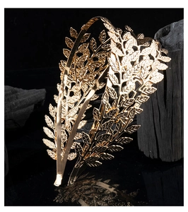 Macro detail of golden metal leaf headband with laurel design on black background