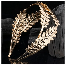 Detail shot of golden laurel leaf double headband against black charcoal backdrop