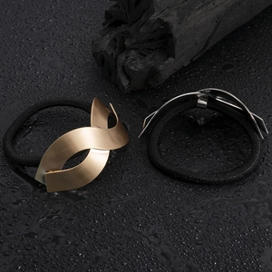 Elastic hair ties with matte gold and silver wave metal accents on wet black background