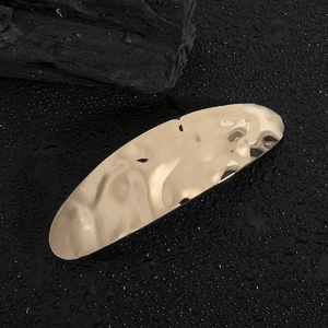 Minimalist gold alloy hair clip with irregular hammer texture on a dark textured background