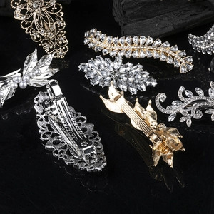 Vintage alloy hair clips set with crystals and pearls on a black reflective background