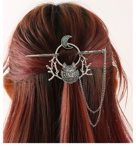 Detail of silver wolf moon hair pin with shell inlay and tassels on red-brown hair