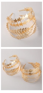 Detailed view of golden alloy headbands with star, leaf, and coin motifs in high polish
