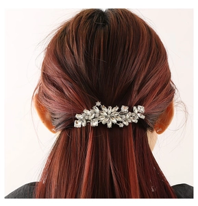Détail de la pince à cheveux fleurie en argent avec strass brillants sur cheveux