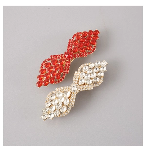 Close-up of red and white crystal hair clips with sparkling rhinestone leaf design