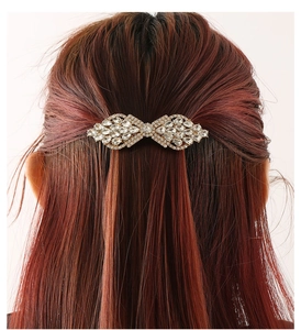 Close-up of sparkling crystal bow hair clip with gold base on long brunette hair