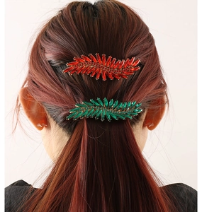 Close-up of leaf-shaped rhinestone hair clips in emerald green and ruby red colors