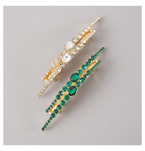 Detail view of gold-plated hair clips set with emerald green and clear rhinestones