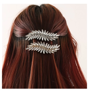 Detail view of rhinestone feather hair clips styled in long reddish brown wavy hair