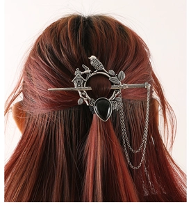 Détail d'un pic à cheveux vintage argenté avec motifs d'oiseaux et pierre noire