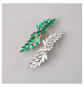 Macro detail of leaf-shaped hair clips with green crystals and silver rhinestones