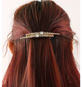 Luxurious gold metal hair clip with rhinestones worn on a model's reddish-brown hair