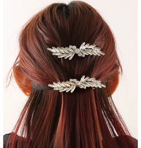 Close-up of sparkling leaf-shaped crystal hair clips worn on reddish-brown hair