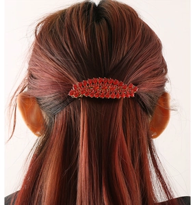 Detailed view of luxury red rhinestone hair clip in feather design on brown hair