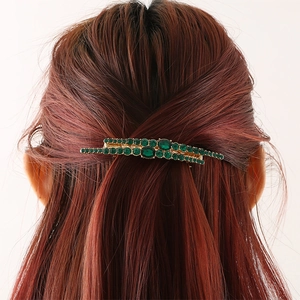 Elegant gold hair clip with emerald green rhinestones worn on reddish brown hair