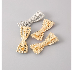 Detail view of bow-shaped alloy hair clips showing the spring clasp back mechanism