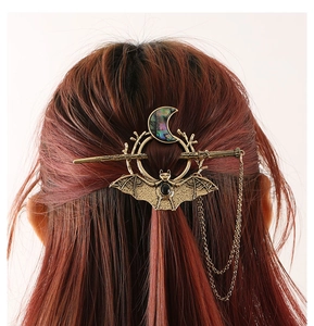 Detailed view of Gothic bat and crescent moon hair pin with tassels on red-brown hair
