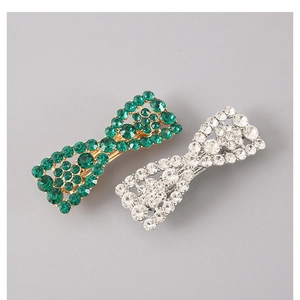 Detail view of sparkling bow hair clips with green and white cubic zirconia stones