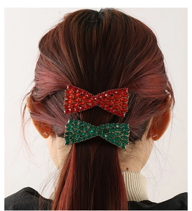 Close-up of red and green bow hair clips with rhinestones on wavy brown hair