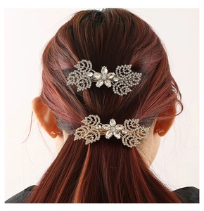 Detailed view of leaf design hair clip with sparkling diamonds on long wavy hair