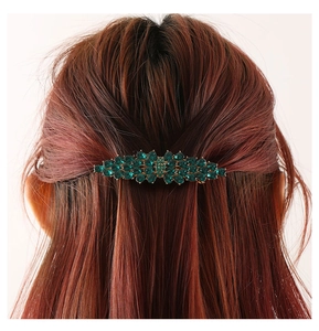 Detailed close-up of emerald green crystal hair clip on model back hairstyle