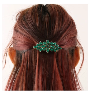 Detail of dark green marquise-cut gems arranged in leaf pattern on golden hair clip
