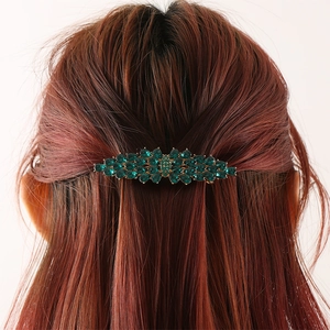 Elegant emerald green rhinestone hair clip with gold base in a shuttle-shaped design