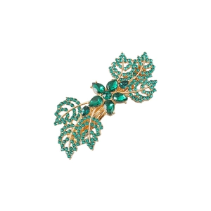 Golden hair clip featuring a maple leaf design with green crystals and small floral accents