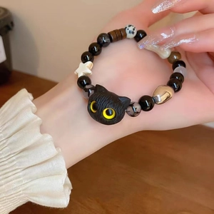 Close-up of black cat bead with yellow eyes on a multi-material beaded bracelet