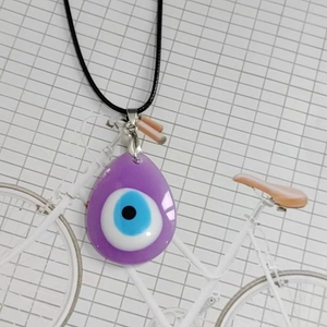 Detalle de un colgante de ojo turco morado con cordón negro para el cuello