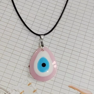 Primer plano del colgante de ojo turco rosa en forma de gota con cordón negro tejido