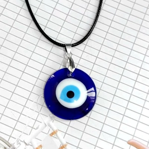 Detalle del colgante circular de cristal ojo turco azul con cordón negro tejido