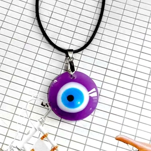 Vista detallada del colgante de ojo de mal de ojo en cristal violeta con cordón negro