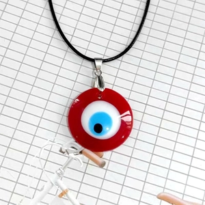 Vista macro detallada del collar con colgante de ojo turco de vidrio rojo de 3cm y cordón