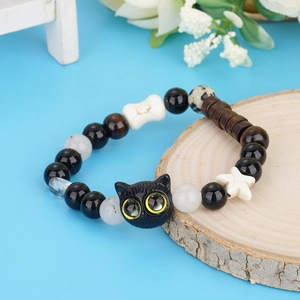 Cute black cat beaded bracelet with cheese and star charms on a rustic wooden slice