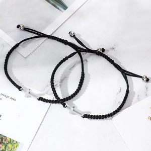 Détail de bracelets croisés noirs tissés réglables sur un fond de marbre blanc élégant