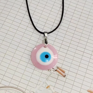 Vista de primer plano del colgante ojo turco rosa de 3cm con cordón negro y broche plata
