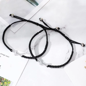 Bracelets tressés noirs faits main avec croix en acier inoxydable sur fond de marbre