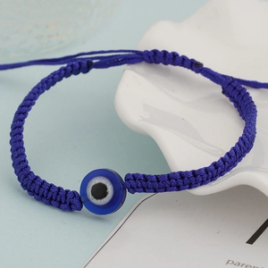 Detail of hand-woven deep blue rope bracelet with a central blue glass evil eye charm