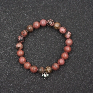 Detalle de pulsera de cuentas de rodonita rosa con colgante de corazón de plata
