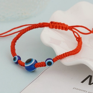 Red woven evil eye bracelet with three blue glass beads and turtle charm detail