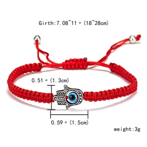 Detail of red woven bracelet with silver Hamsa Hand and blue evil eye bead pendant