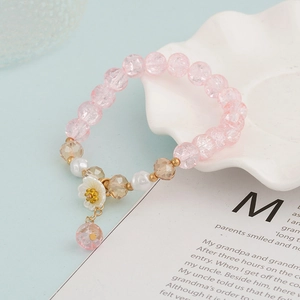 Detail of pink crystal beaded bracelet featuring white floral charm and pearl accents