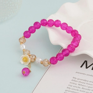 Detailed macro view of a beaded bracelet with pink crystals and a white flower charm