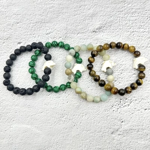 Dettaglio di quattro braccialetti di perline con malachite e ciondoli a delfino bianco