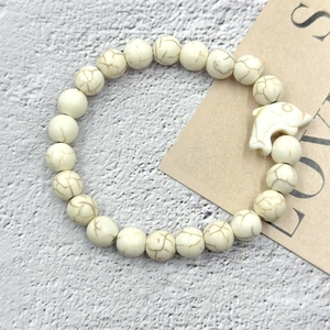 Dettaglio di braccialetto in perline di turchese bianco con ciondolo a forma di delfino intagliato