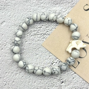 Dettaglio del bracciale elastico in turchese bianco con un ciondolo a forma di delfino